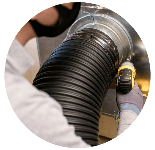 Air duct cleaning technician connecting vacuum to furnace in Phoenix home.